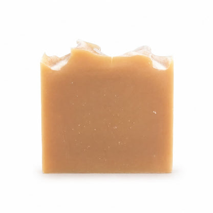 A rectangular bar of Jarhead Aromatics Lemongrass Handmade Natural Goat Milk Artisan Soap, featuring a light brown hue and an uneven, wavy top edge, is displayed against a plain white background.