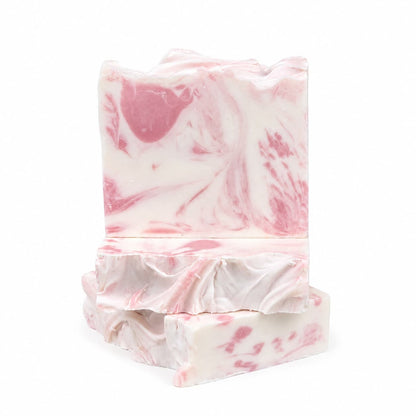 Three rectangular bars of Jarhead Aromatics’ Magnolia + Lavender Handmade Coconut Milk Artisan Soap, featuring delicate pink and white marbled swirls, are stacked against a plain white background. The uneven, textured edges enhance the artisanal look of this handcrafted floral soap, known for its soft magnolia and calming lavender scent.