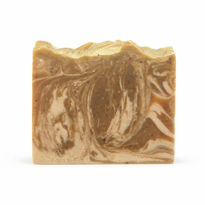 A rectangular bar of Jarhead Aromatics Mahogany + Coconut Handmade Coconut Milk Artisan Soap, featuring marbled brown and beige hues with a rough, uneven top edge, is displayed against a plain white background.
