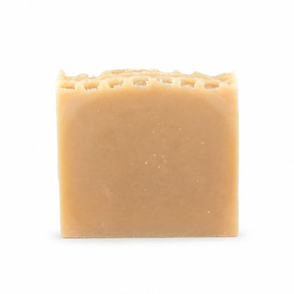 A rectangular, beige bar of Jarhead Aromatics Milk + Honey Handmade Natural Goat Milk Artisan Soap, featuring a textured top edge, is displayed against a plain white background.