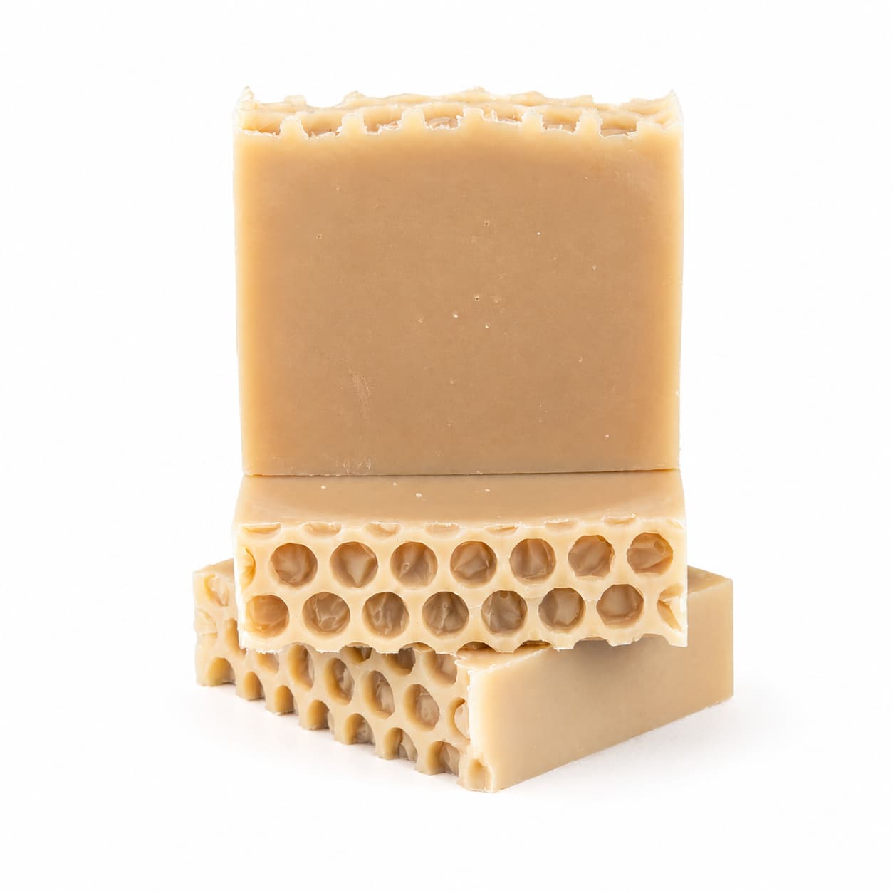 Three beige bars of Jarhead Aromatics’ Milk + Honey Handmade Natural Goat Milk Artisan Soap are stacked, each showcasing a honeycomb-like pattern on one side. The creamy, natural soap bars are set against a plain white background.