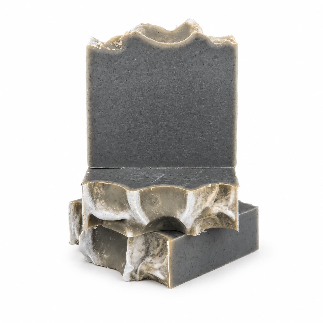 Two dark gray, rectangular bars of Mugwort + Lavender Handmade Natural Artisan Soap by Jarhead Aromatics, each with wavy, uneven tops and carved curves along the sides, are stacked on a white background.