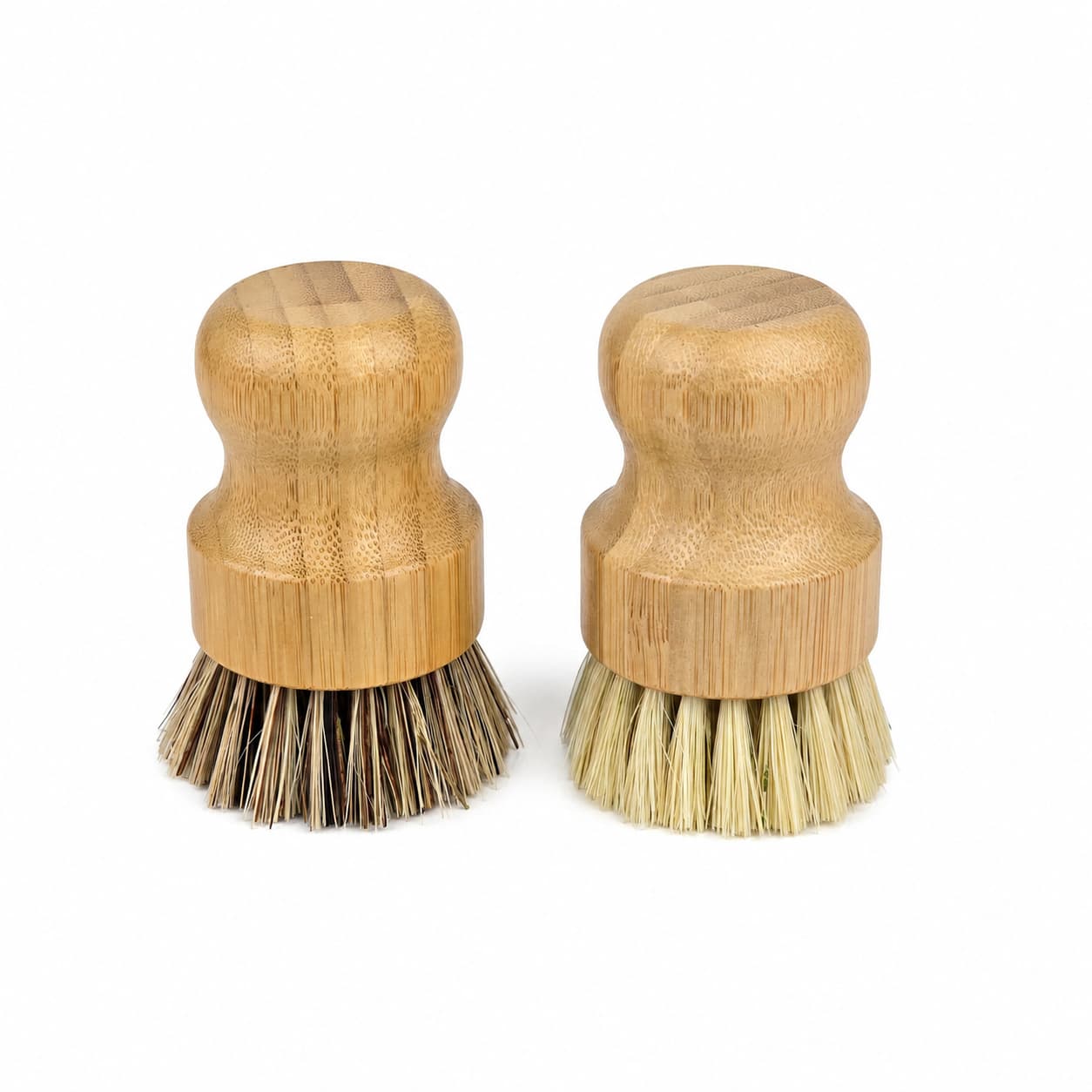A pair of Jarhead Aromatics Bamboo Handle Palm & Sisal Fiber Scrubber Brushes, each with a natural wooden handle and round top—one with darker bristles and one with lighter—are displayed side by side on a white background. This eco-friendly set of natural kitchen cleaning brushes is perfect for sustainable cleaning routines.