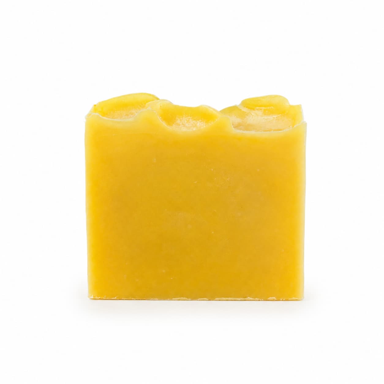 A rectangular yellow bar of Jarhead Aromatics Orange + Carrot Handmade Natural Artisan Soap, featuring a wavy, uneven top edge and set against a plain white background.