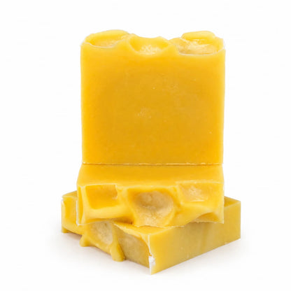 Two vibrant yellow-orange bars of Jarhead Aromatics’ Orange + Carrot Handmade Natural Artisan Soap—Sweet Orange & Carrot Juice Soap—are stacked, one upright and one lying flat, each showcasing an uneven, textured top. The artisan-crafted bars evoke the fresh color of orange carrot soap and stand out against a plain white background.