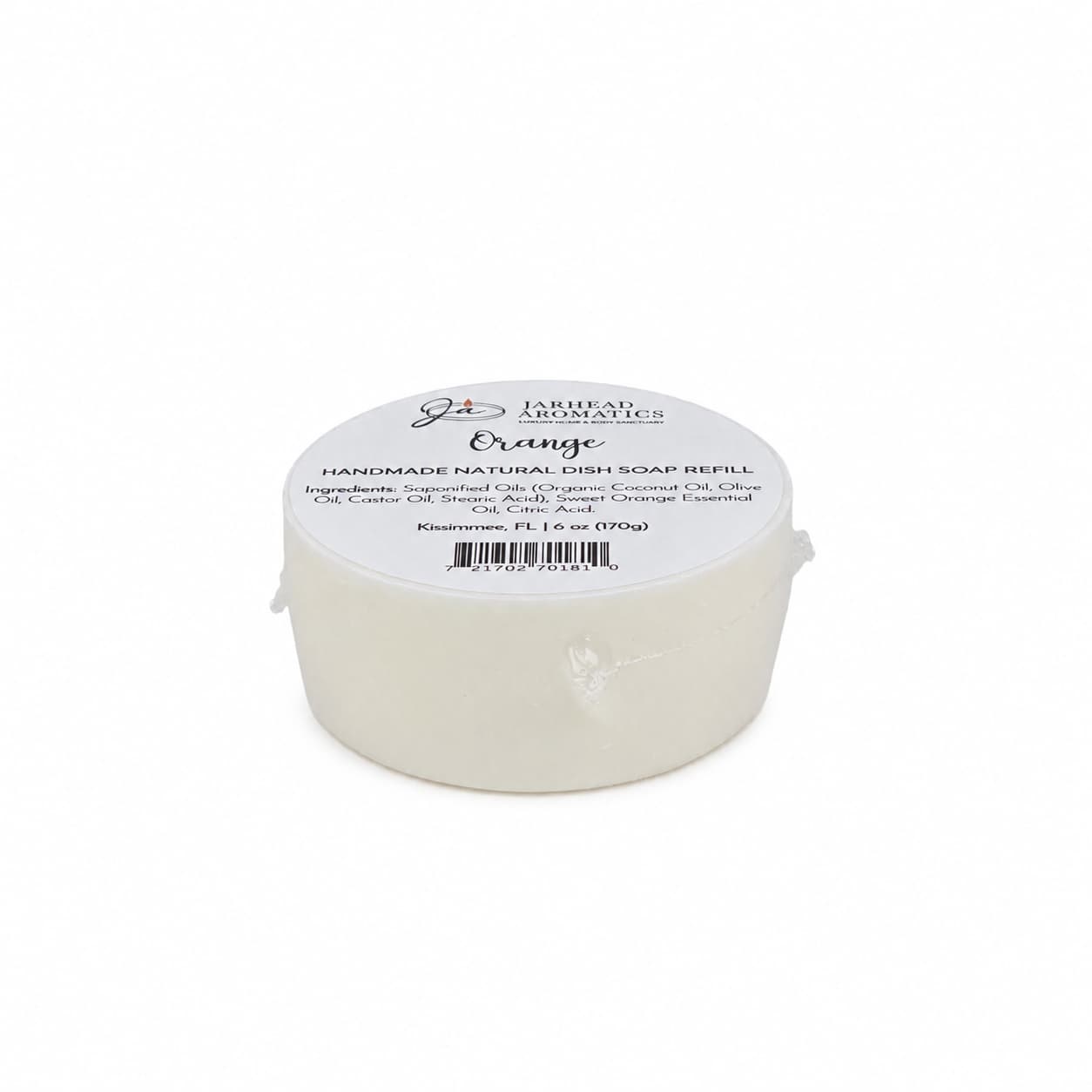 A round white handmade natural solid dish soap refill from Jarhead Aromatics, labeled with the scent “Orange,” ingredients, and a weight of 1.1 oz. This plant-based Orange Handmade Natural Solid Dish Soap | Citrus Kitchen Cleaning Bar with Essential Oils is wrapped in plastic and features a white top label displaying branding details.
