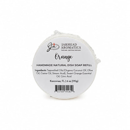 Round white soap bar labeled Jarhead Aromatics Orange Handmade Natural Solid Dish Soap, a citrus kitchen cleaning bar with essential oils. This plant-based formula includes a detailed ingredients list, weighs 6 oz (170g), and is made in Kissimmee, FL—making it an eco-friendly kitchen essential.