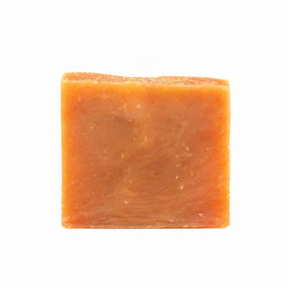 A square bar of Orange + Lemongrass Natural Handmade Goat Milk Soap in an orange citrus scent.