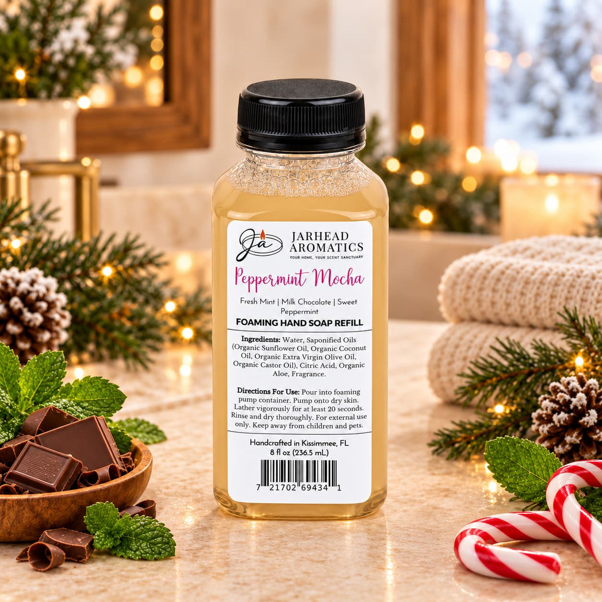 A bottle of Peppermint Mocha Handmade Foaming Hand Soap | Chocolate Mint & Vanilla sits on a counter with chocolate pieces, fresh mint leaves, and a candy cane.