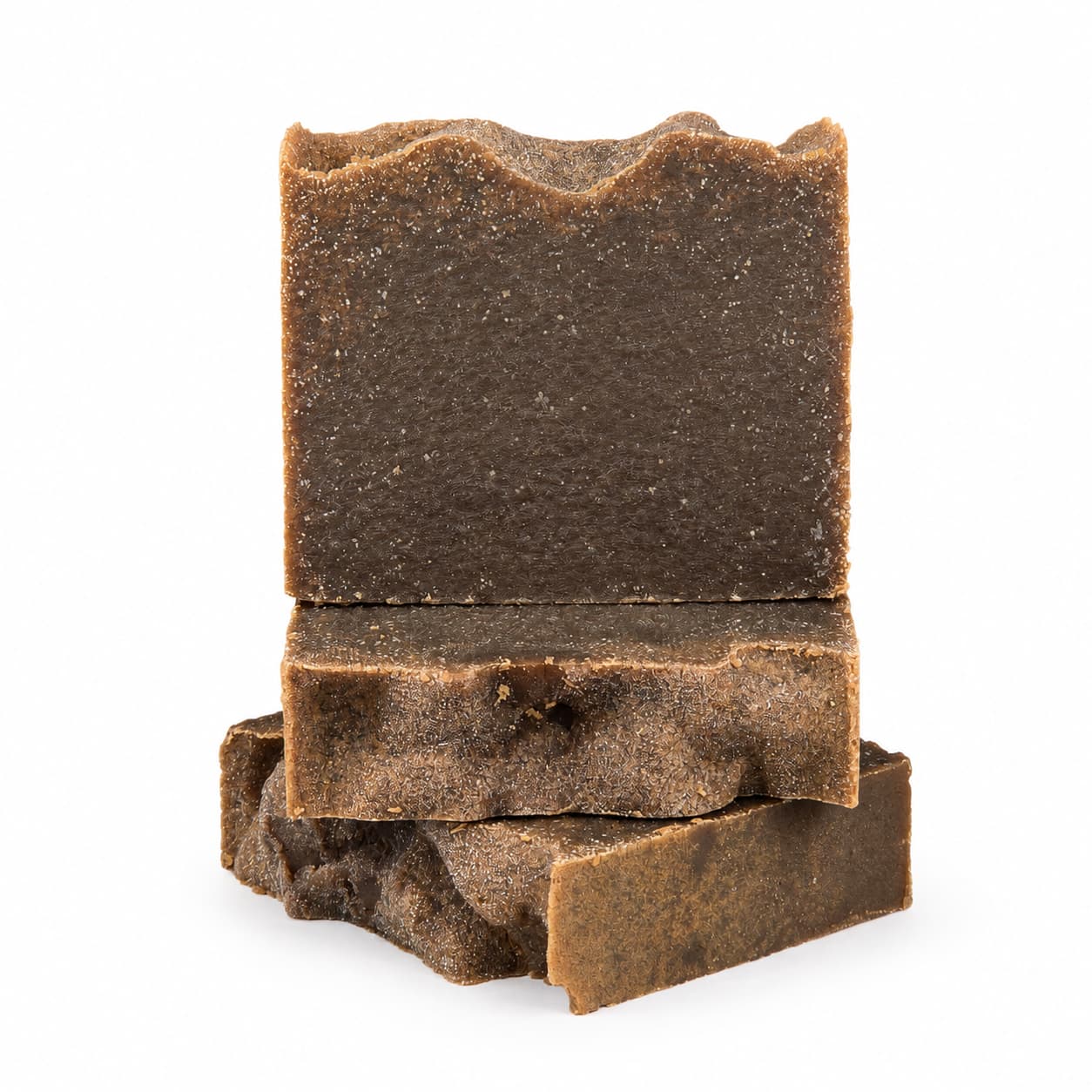 Three uneven, rectangular bars of Jarhead Aromatics Pine Tar Handmade Natural Artisan Soap are stacked on top of each other against a white background. The smoky pine and cedarwood soap features a rough, textured surface and slightly jagged edges.