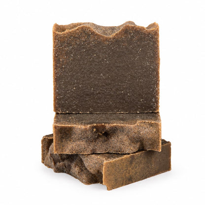 Three uneven, rectangular bars of Jarhead Aromatics Pine Tar Handmade Natural Artisan Soap are stacked on top of each other against a white background. The smoky pine and cedarwood soap features a rough, textured surface and slightly jagged edges.