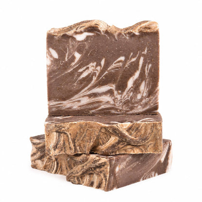 Three rectangular bars of Jarhead Aromatics’ Porter + Coffee Handmade Craft Beer Artisan Soap are stacked, with one upright on top of two lying flat. The marbled brown soap features wavy patterns, a rustic texture, and is crafted with roasted coffee and cocoa for natural exfoliation. The background is plain white.