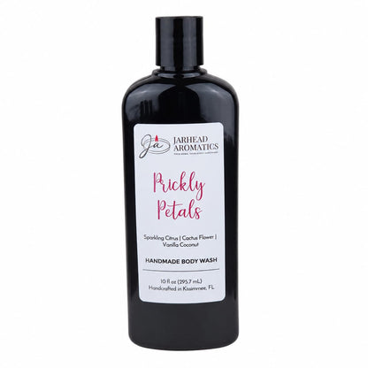 A 10 fl oz black bottle of Jarhead Aromatics Prickly Petals Handmade Body Wash features a white label detailing scent notes of sparkling citrus, cactus flower, and vanilla coconut. This moisturizing body wash is crafted with organic aloe and plant-based oils.