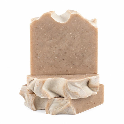 Three bars of Jarhead Aromatics’ Pumpkin + Spice Handmade Artisan Soap are stacked on a white background. The top bar of this spiced pumpkin exfoliating soap features a slightly jagged edge, while the two below showcase wavy, marbled textures. Each rustic brown bar is infused with the warm autumn fragrance signature to this handmade artisan collection.