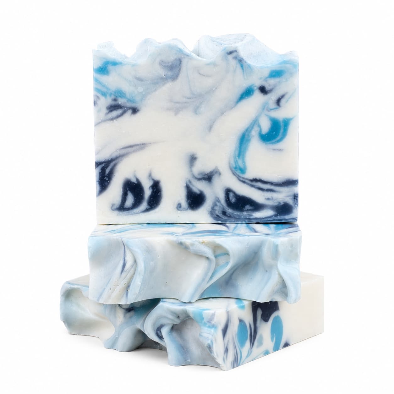 Three Jarhead Aromatics Rosemary + Eucalyptus Handmade Coconut Milk Artisan Soap bars, featuring swirling blue, black, and white patterns, are stacked against a white background. These Fresh Herbal Spa Soap bars have textured, wavy tops and smooth sides that resemble ocean waves.