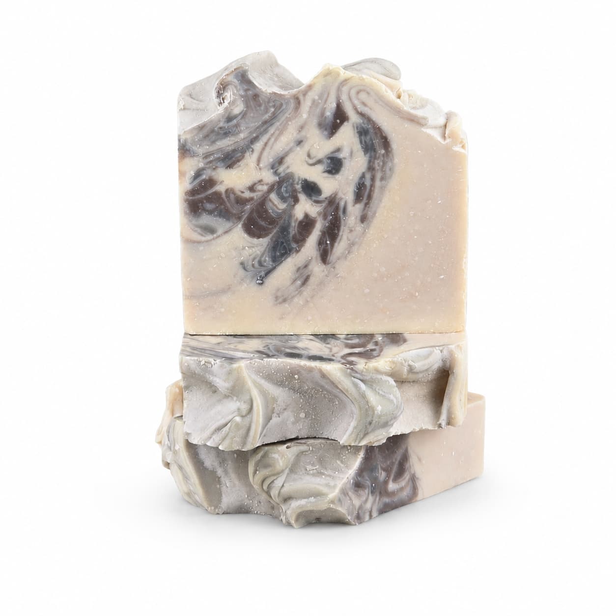 Two rectangular bars of Jarhead Aromatics Sandalwood + Patchouli Handmade Artisan Soap, featuring marbled swirls of gray, white, and beige, are stacked on top of each other against a plain white background. The rugged, textured edges showcase the natural beauty and craftsmanship of this earthy woodsy charcoal soap.