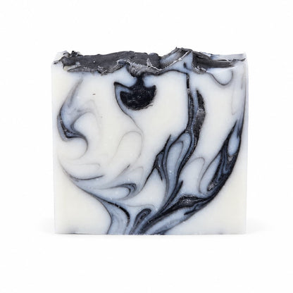 A rectangular bar of Jarhead Aromatics Tea Tree + Charcoal Handmade Natural Tallow Artisan Soap, featuring intricate black and gray swirling patterns and a textured, uneven top edge, set against a plain white background.