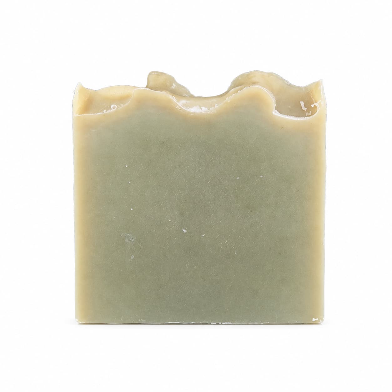 A rectangular bar of Tea Tree Handmade Natural Goat Milk Artisan Soap by Jarhead Aromatics, featuring a greenish hue and uneven, wavy top edges, set against a plain white background.