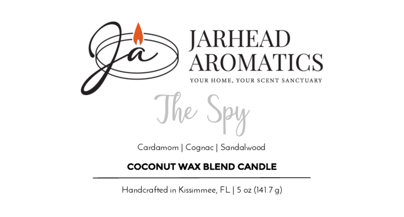 A label for Jarhead Aromatics The Spy Handmade Non-Toxic Coconut Wax Blend Candle, 5 oz ceramic container, featuring cardamom, cognac, and patchouli sandalwood fragrance. Handcrafted in Kissimmee, FL.