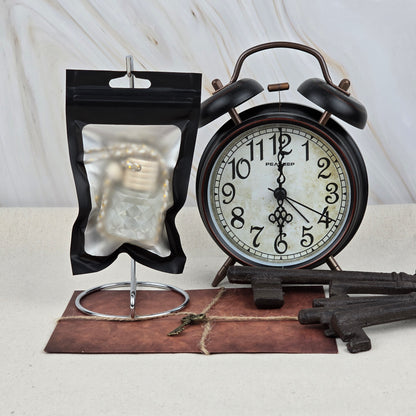 A black alarm clock, antique keys, a small key on an envelope, and a clear pouch holding Jarhead Aromatics’ Sweet Sunrise Car Diffuser | Bright Citrus & Peach Car Air Freshener are arranged on a light surface against a marble background.