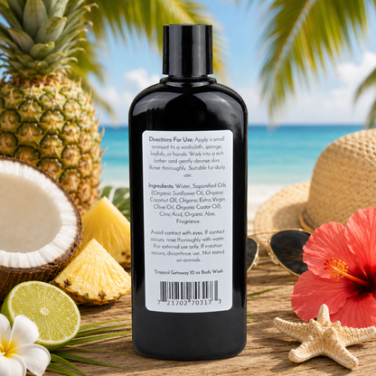 A black bottle of Jarhead Aromatics Tropical Getaway Handmade Body Wash with Organic Aloe & Plant-Based Oils rests on wood, surrounded by pineapple, coconut, lime, palm leaves, a red hibiscus flower, and a beach in the background.