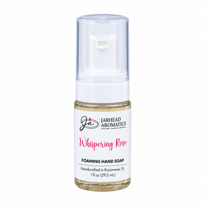 A small, clear plastic bottle of Jarhead Aromatics Whispering Rose Handmade Foaming Hand Soap with a white pump dispenser and a label that reads Whispering Rose Foaming Hand Soap.