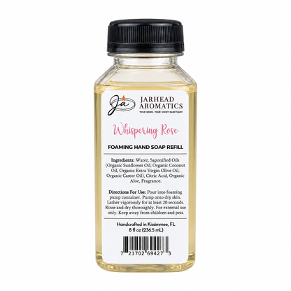 A clear plastic bottle of Jarhead Aromatics Whispering Rose Handmade Foaming Hand Soap refill with a black cap and a white label featuring product ingredients, usage instructions, and a barcode.