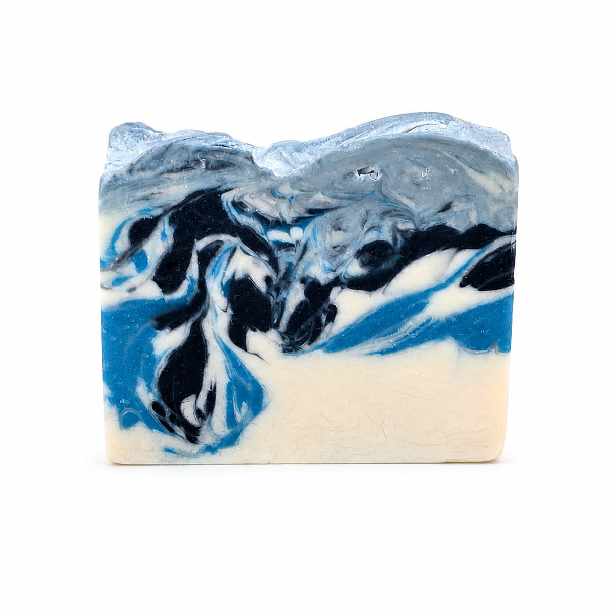 Winter Wonderland Handmade Coconut Milk Artisan Soap features a swirled pattern of white, bright blue, and dark blue, topped with a textured, pale blue layer.