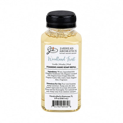 Clear plastic bottle of Jarhead Aromatics Woodland Frost Handmade Foaming Hand Soap with a black pump cap and a label detailing the ingredients, usage instructions, and product name.