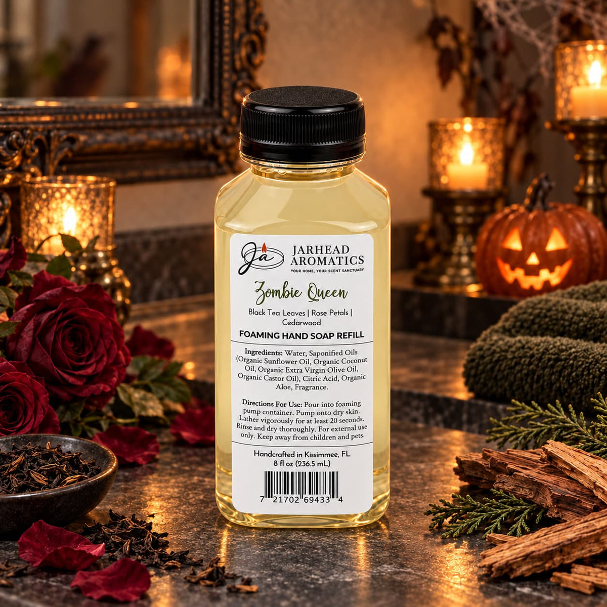 A bottle of Zombie Queen Handmade Foaming Hand Soap | Black Tea, Rose Petals & Cedarwood sits surrounded by red roses, loose tea leaves, and cedar wood chips on a dark surface.